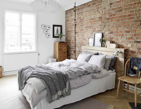 Kamar dengan dinding bata ekspos dan furnitur kayu alami